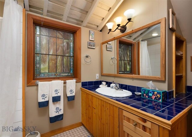 bathroom featuring vanity and lofted ceiling with beams