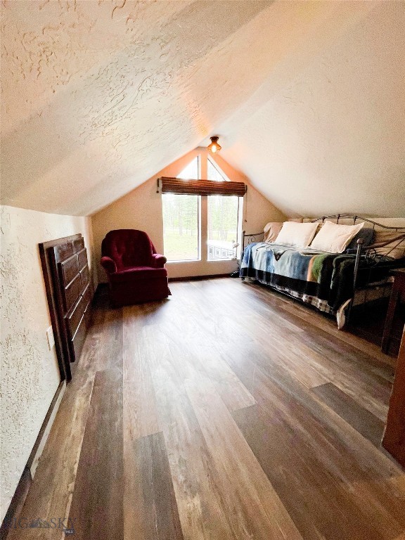 unfurnished bedroom with lofted ceiling, hardwood / wood-style floors, and a textured ceiling