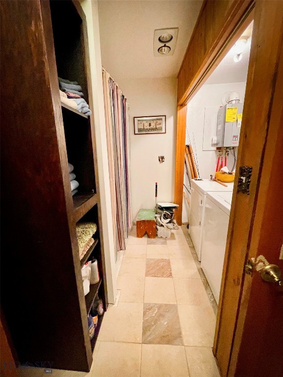 hallway featuring separate washer and dryer, water heater, and light tile patterned floors