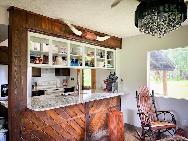 kitchen with light stone countertops, kitchen peninsula, and a textured ceiling