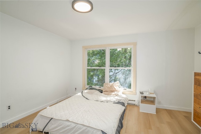 bedroom with baseboard heating and light hardwood / wood-style flooring