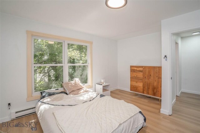 bedroom with light wood-type flooring and a baseboard heating unit