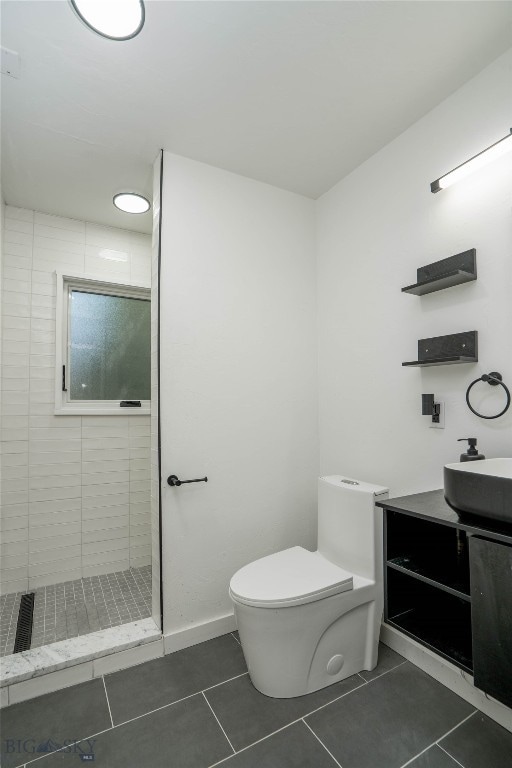 bathroom featuring tiled shower, tile patterned flooring, vanity, and toilet