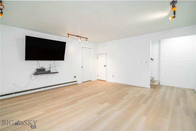 unfurnished living room featuring rail lighting, light hardwood / wood-style floors, and a baseboard heating unit