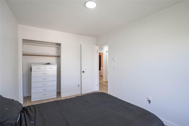 unfurnished bedroom with a closet and light wood-type flooring