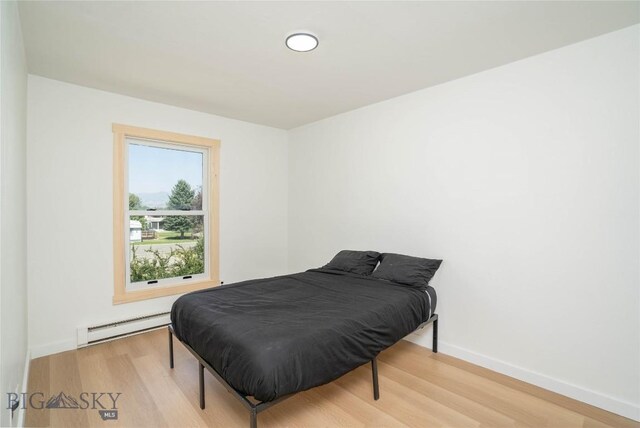 bedroom featuring baseboard heating and light hardwood / wood-style flooring