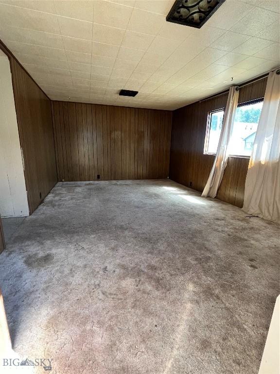 carpeted spare room featuring wood walls