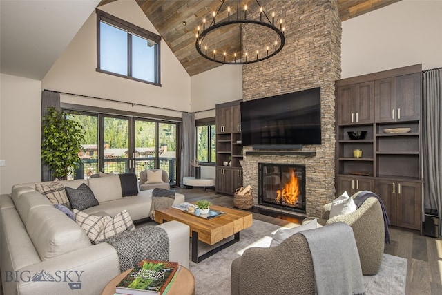 living room featuring light wood-type flooring, high vaulted ceiling, an inviting chandelier, a stone fireplace, and wood ceiling