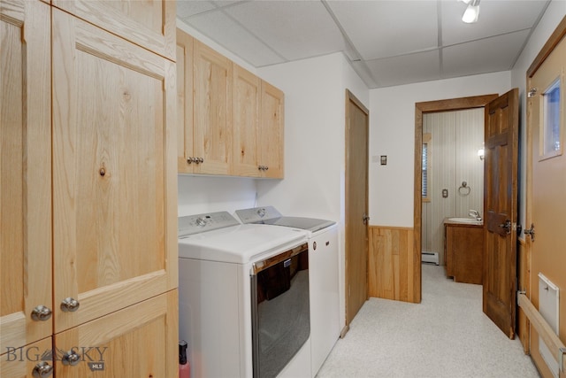 laundry room with cabinets, washer and clothes dryer, a baseboard radiator, sink, and wooden walls