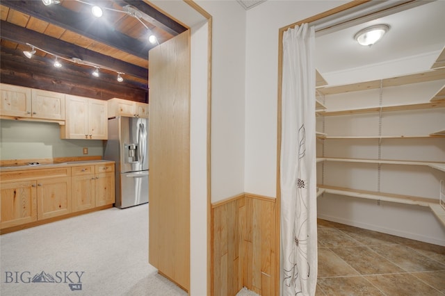 kitchen with track lighting, wooden walls, light tile patterned floors, stainless steel fridge with ice dispenser, and light brown cabinets