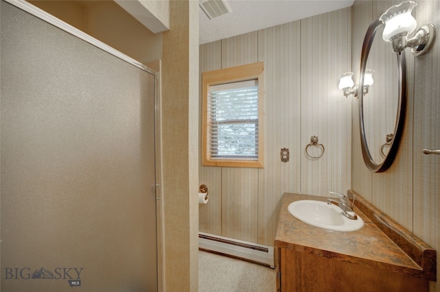 bathroom featuring a baseboard heating unit, vanity, a textured ceiling, and walk in shower