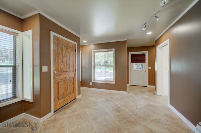 foyer entrance with crown molding, track lighting, and light tile patterned floors