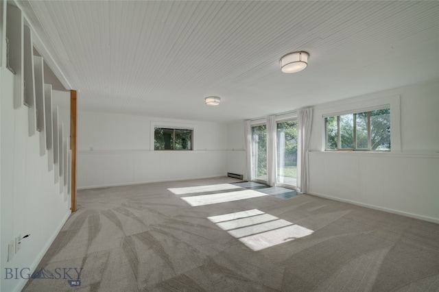 carpeted spare room with a baseboard heating unit