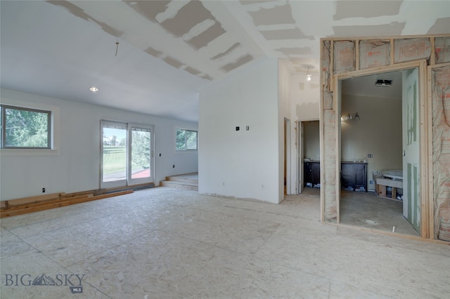 unfurnished living room with lofted ceiling and plenty of natural light