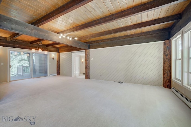 8733 Huffman, Bozeman, MT 59715 - unfurnished living room featuring beam ceiling, a wealth of natural light, a baseboard heating unit, and carpet