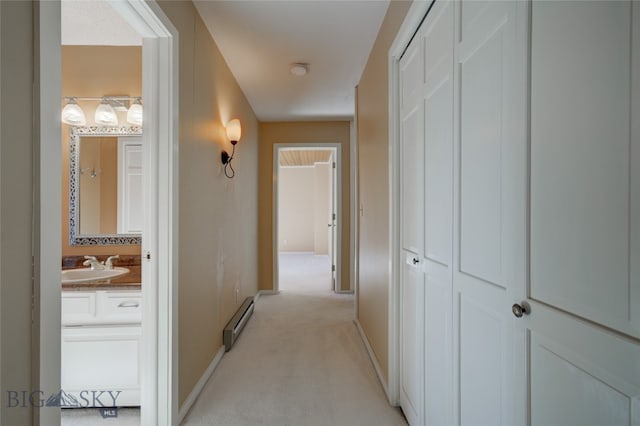 corridor with a baseboard radiator, sink, and light carpet