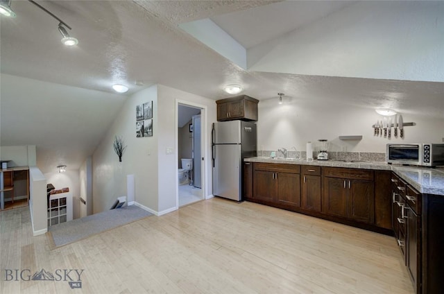 8733 Huffman, Bozeman, MT 59715 - kitchen with lofted ceiling, stainless steel appliances, and dark brown cabinets