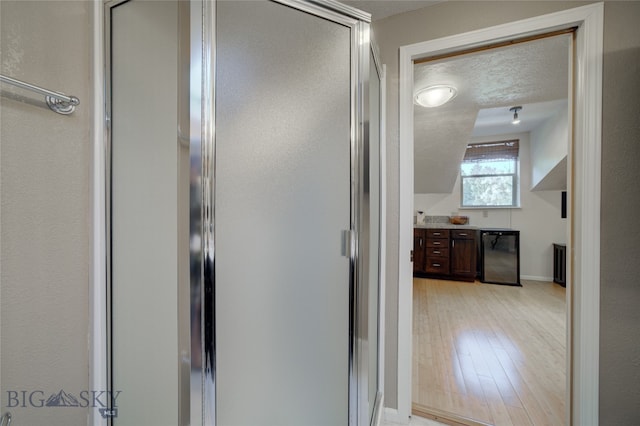 bathroom featuring a textured ceiling, vanity, a shower with shower door, and wood-type flooring