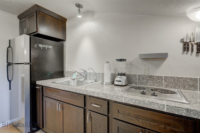 kitchen featuring stainless steel refrigerator, electric stovetop, a textured ceiling, sink, and vaulted ceiling