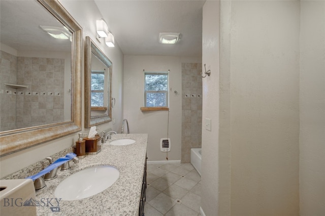 bathroom featuring tiled shower / bath, vanity, heating unit, and tile patterned flooring