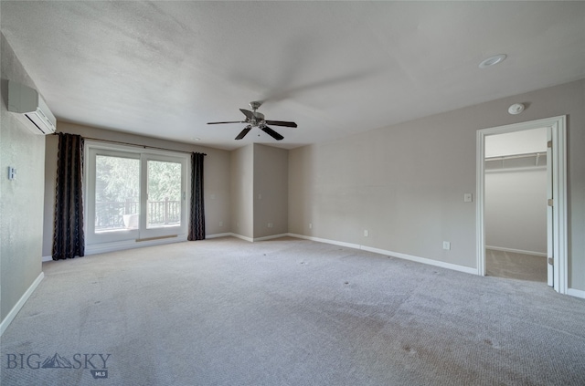 empty room featuring carpet flooring, ceiling fan, and a wall mounted air conditioner