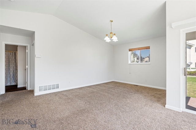 carpeted spare room with vaulted ceiling and an inviting chandelier