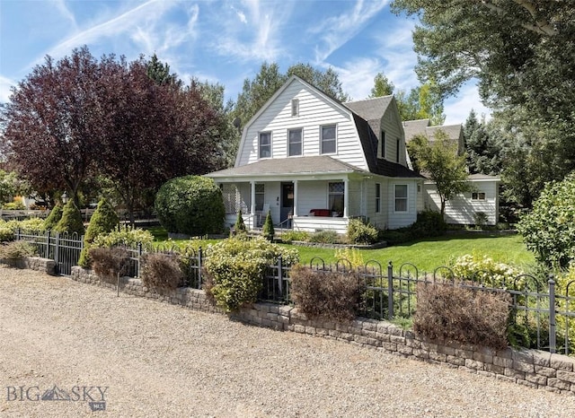 view of front of house with a gambrel roof, a front lawn, covered porch, and a fenced front yard