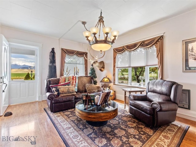 living area with baseboards, wood finished floors, and a notable chandelier