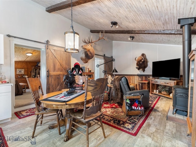 dining room featuring light wood-type flooring, wood ceiling, and a barn door