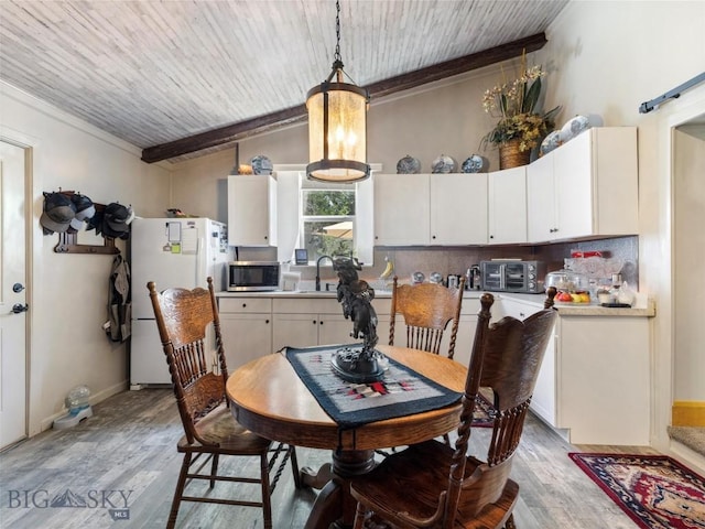 dining space featuring light wood finished floors, vaulted ceiling, wooden ceiling, and ornamental molding