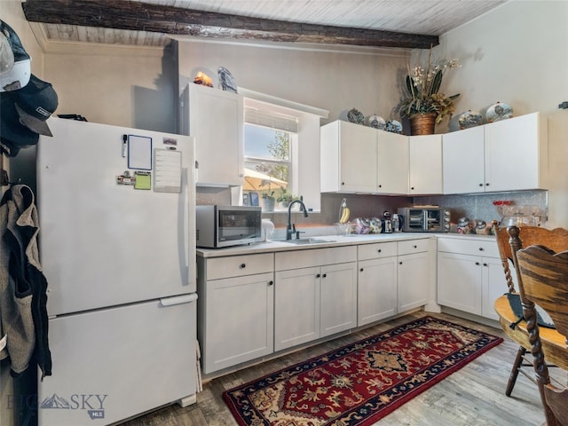 kitchen with tasteful backsplash, sink, dark wood-type flooring, white refrigerator, and white cabinets