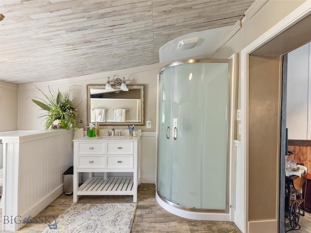 full bathroom with a shower stall, vanity, wood finished floors, and wainscoting