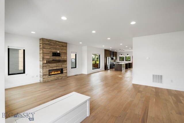 living room featuring a tiled fireplace and light wood-type flooring