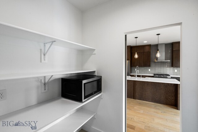 kitchen with pendant lighting, wall chimney range hood, tasteful backsplash, appliances with stainless steel finishes, and sink