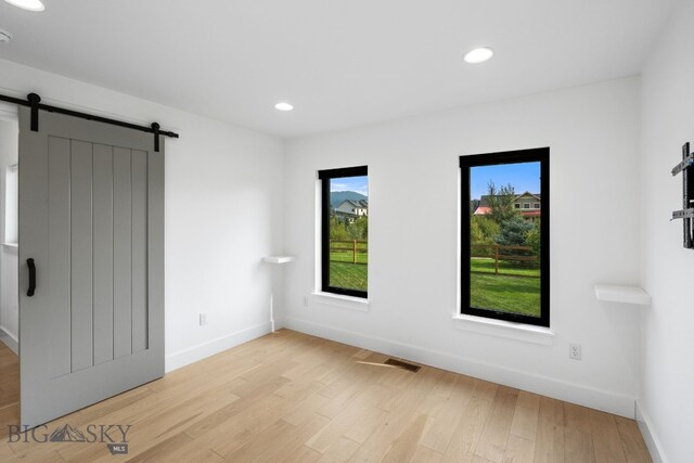 spare room with light hardwood / wood-style floors and a barn door