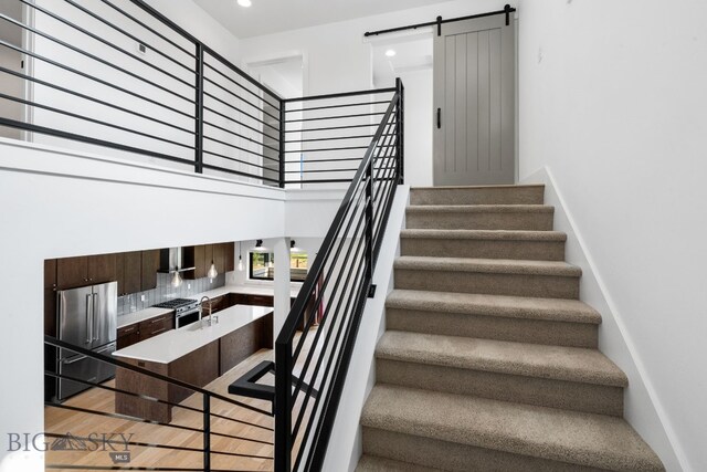 stairway featuring sink, wood-type flooring, and a barn door