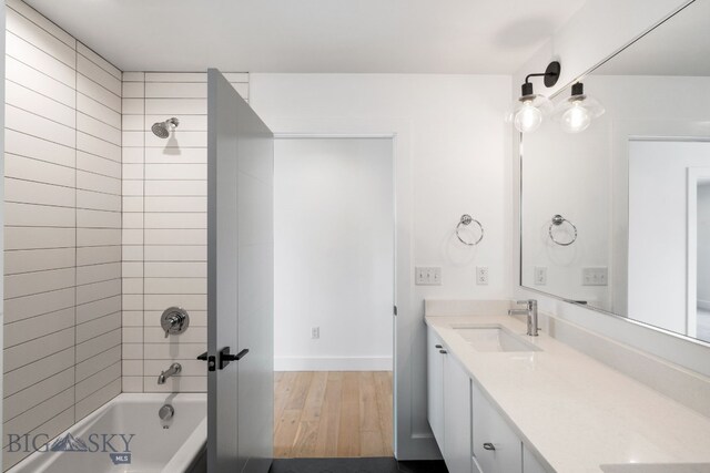 bathroom with wood-type flooring, vanity, and tiled shower / bath combo