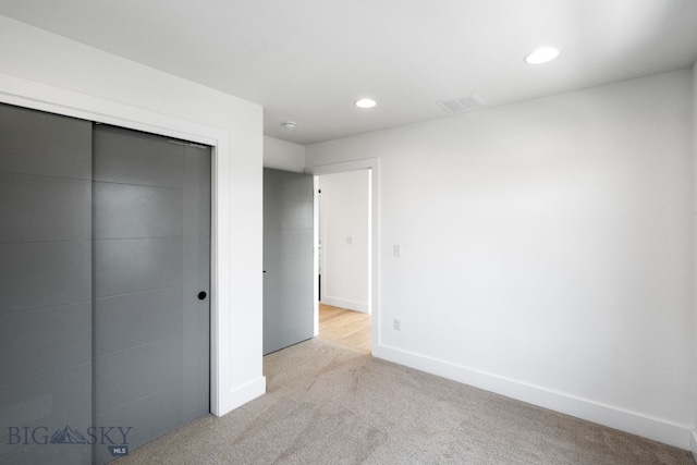 unfurnished bedroom featuring a closet and light colored carpet