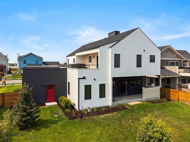 rear view of property featuring a balcony, a patio, and a yard