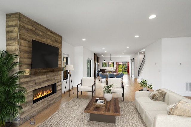 living room with a tile fireplace and light wood-type flooring