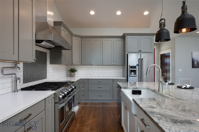 kitchen with light stone countertops, dark hardwood / wood-style flooring, high quality appliances, wall chimney exhaust hood, and tasteful backsplash