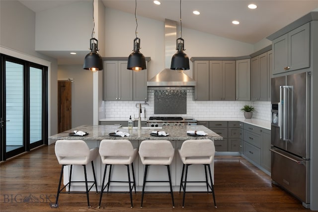 kitchen with a kitchen island with sink, dark wood-type flooring, stainless steel appliances, and a kitchen breakfast bar