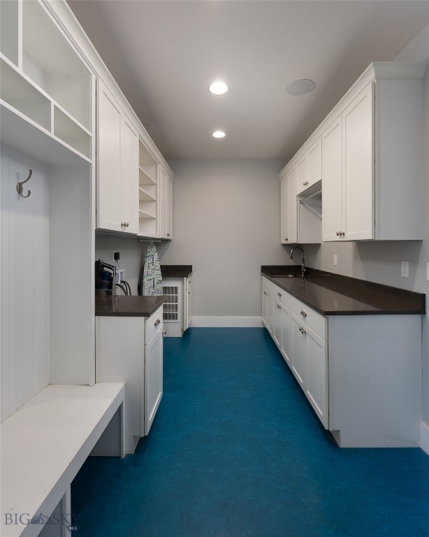 kitchen with sink, dark colored carpet, and white cabinetry