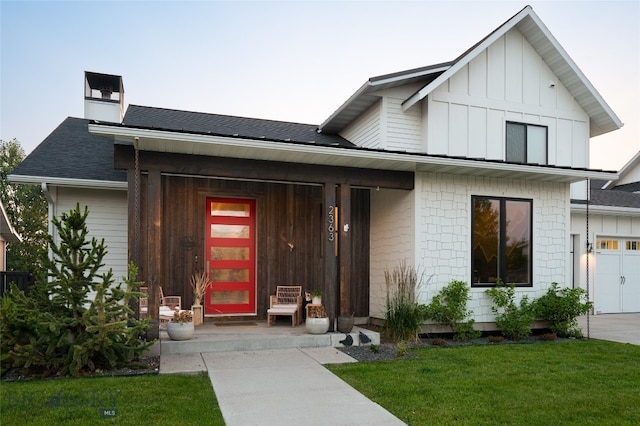 view of front of home featuring a porch, a garage, and a front lawn