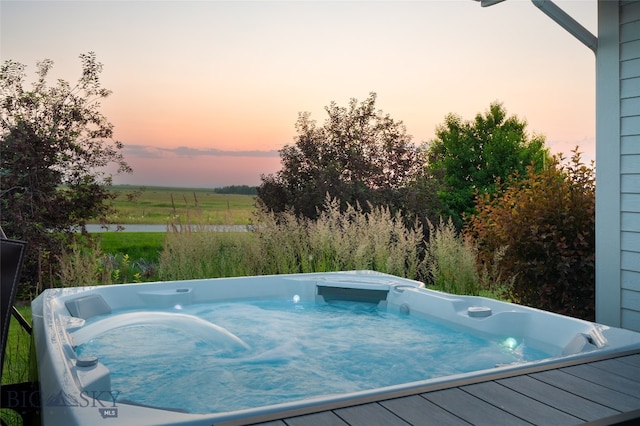 pool at dusk with an outdoor hot tub