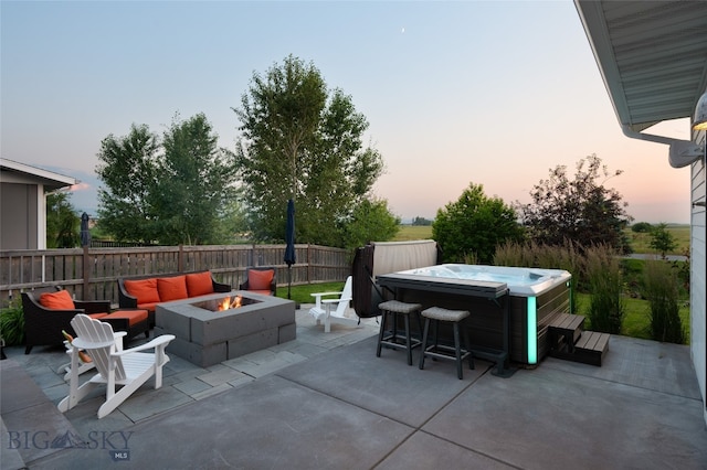 patio terrace at dusk with a fire pit and a hot tub