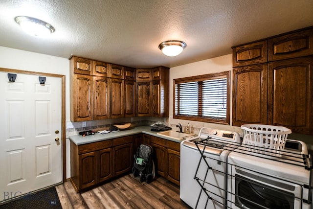 kitchen with dark wood-type flooring, a textured ceiling, washer and clothes dryer, and sink