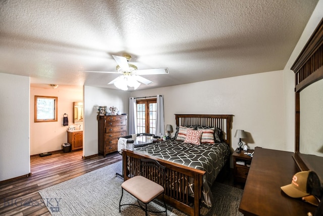 bedroom with a textured ceiling, dark wood-type flooring, ceiling fan, and ensuite bath