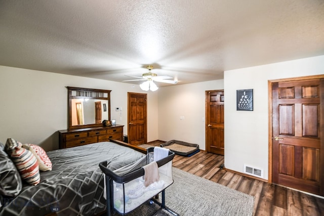 bedroom featuring dark wood-type flooring, a textured ceiling, and ceiling fan