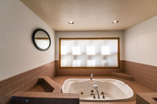 bathroom featuring tiled tub and a textured ceiling